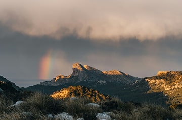 A mountain range with an iridescent cloud behind it