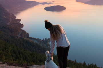 hiker on mountainside overlooking lake