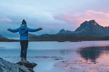 hiker enjoying lake view, mountains behind