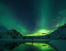 aurora borealis over lake and snowy mountains