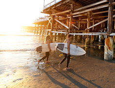 surfers walking by pier on beach