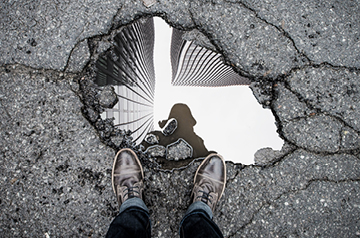 mirror-like reflection of city buildings in puddle