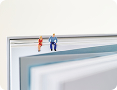 Toy figures sitting on textbook spine