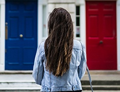 woman standing in front of red door and blue door