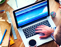 hand on keyboard with 'Stock Exchange' and chart on screen