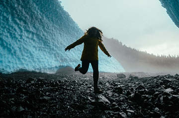 walking on rocky shore between walls of ice